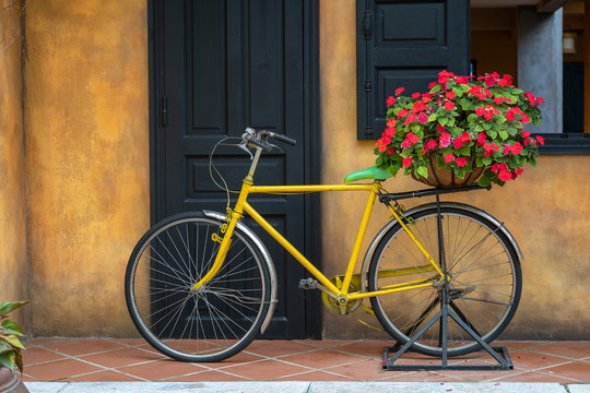 Yellow vintage bike with basket full of flowers next to an old building in Danang, Vietnam