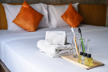 Set of hotel amenities (such as towels, shampoo, soap, glass, toothbrush etc) on the bed. Hotel amenities is something of a premium nature provided in addition to the room when renting a room.