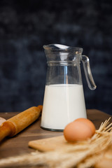 Baking cooking Ingredients flour eggs rolling pin milk and kitchen textile. Side and top view. Delicious food, recipes, cooking, gastronomy, on a dark background and wooden table.