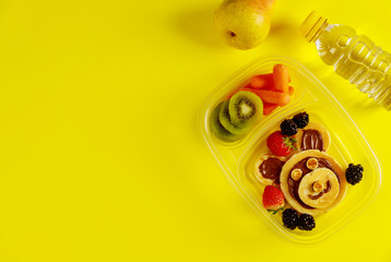 Tasty food in lunch boxes on yellow background.