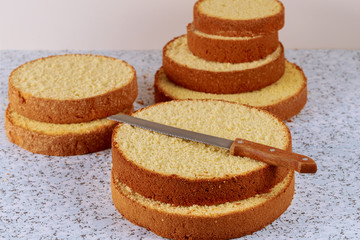 Sliced sponge cake with knife on table for making wedding cake.