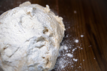 a piece of wheat dough for pies and pizza on a wooden background on the side of the frame. Close-up, selective focus