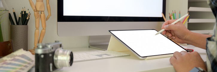 Cropped shot of male photographer working with mock-up tablet on office desk