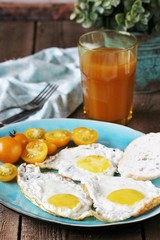 sunny breakfast life style, fried eggs and yellow cherry tomatoes. on a blue plate. yellow and blue