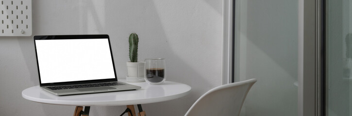 Cropped shot of portable workspace with mock-up laptop, coffee cup and cactus pot