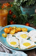sunny breakfast life style, fried eggs and yellow cherry tomatoes. on a blue plate. yellow and blue