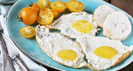 sunny breakfast life style, fried eggs and yellow cherry tomatoes. on a blue plate. yellow and blue