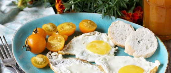 sunny breakfast life style, fried eggs and yellow cherry tomatoes. on a blue plate. yellow and blue