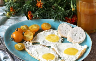 sunny breakfast life style, fried eggs and yellow cherry tomatoes. on a blue plate. yellow and blue