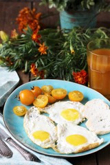 sunny breakfast life style, fried eggs and yellow cherry tomatoes. on a blue plate. yellow and blue