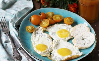 sunny breakfast life style, fried eggs and yellow cherry tomatoes. on a blue plate. yellow and blue