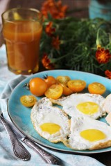 sunny breakfast life style, fried eggs and yellow cherry tomatoes. on a blue plate. yellow and blue