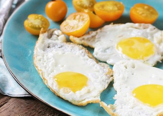 sunny breakfast life style, fried eggs and yellow cherry tomatoes. on a blue plate. yellow and blue