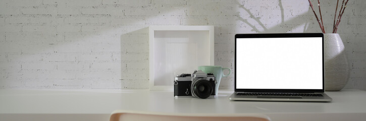 Close up view of minimal workspace with blank screen laptop, camera, decorations and copy space on white table