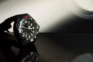 Modern men's wristwatch with reflection in the background.