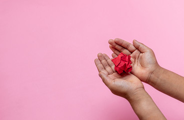 Hand holding crumpled paper or white paper ball on pink background. - fail creativity concept.