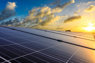 Photovoltaic solar panels and high voltage power lines at sunset sky background,green clean alternative energy.