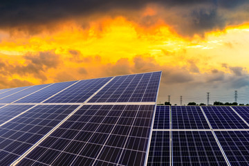 Photovoltaic solar panels and high voltage power lines at sunset sky background,green clean...