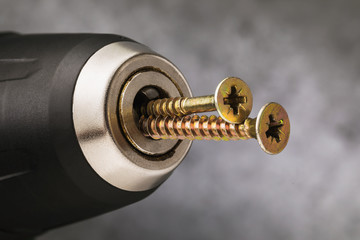 Self-tapping screws are inserted into the power tool with the reverse side. Concept on the misuse of a screwdriver