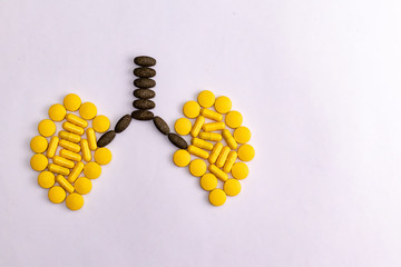 Black and yellow herbal tablets in a lung shape on white background with copy space. Respiratory...