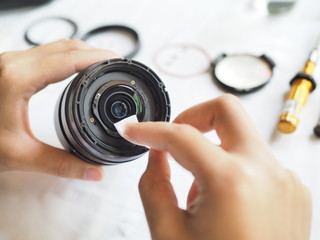 Technician holding and cleaning inside lens with lens cleaning paper.