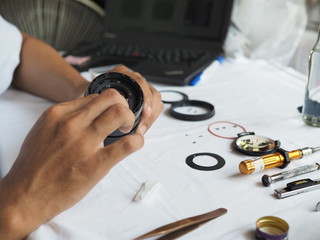Technician holding and cleaning inside lens with lens cleaning paper.