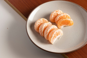 Cascos de mandarina en plato beige. Comida durante pandemia. Alimentación saludable de frutas