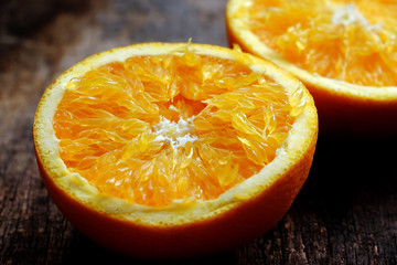 Close up from high view of yellow orange fruit cut two in half on wooden background