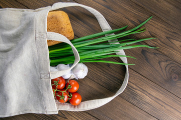 Woven bag of different health food on dark wooden table background. Bread, green onion, garlic,...
