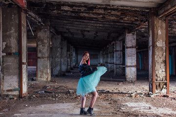 Fototapeta na wymiar Portrait of a young girl with pink hair standing inside of collapsed building surrounded by ruins