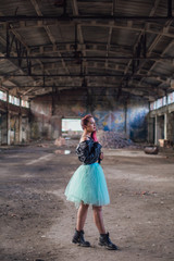 Portrait of a young girl with pink hair standing inside of collapsed building surrounded by ruins