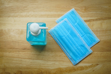 Hand sanitizer alcohol gel and surgical masks on the wooden table with top view