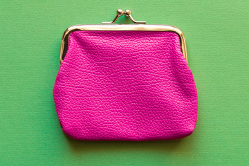 Fashionable pink wallet on a light green background. Close up.