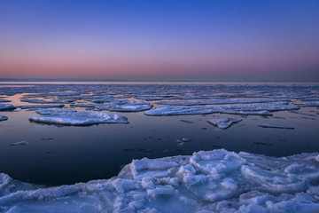 Blocks of ice in the sea against a lilac sunset sky

