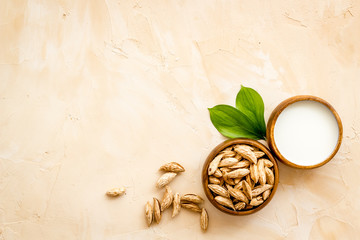 Alternative milk made from almond. Drink near unpeeled on beige table top-down copy space