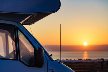 Camper car on coast at sunrise
