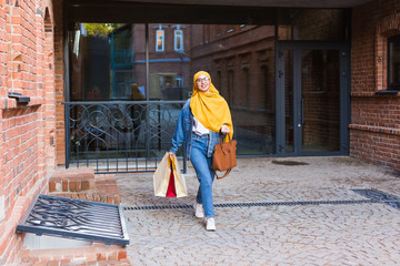 Obraz na płótnie Canvas Sale and buying concept - Happy arab muslim girl with shopping bags after mall