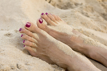 Woman manicured feet in beach sand
