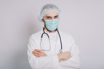 Doctor with a stethoscope in a white coat and a medical mask on a white background, studio photo