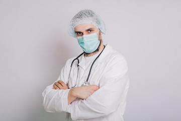 Doctor with a stethoscope in a white coat and a medical mask on a white background, studio photo