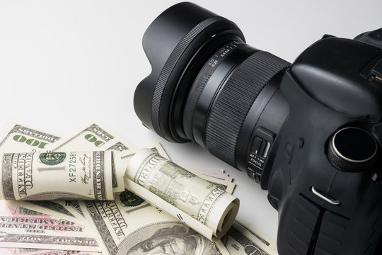 A black digital camera on banknotes with white background.