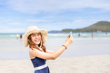 woman in sunny day smile and hold mobile phone on summer beach. holidays on tropical beach.