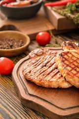 Board with cooked pork steaks on table