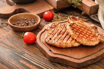 Board with cooked pork steaks on table
