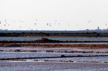 evocative image of salt pans in the foreground
with kytesurf sails and windmills in the background