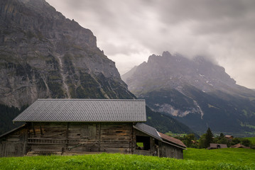 An alpine farm hut surrounded by Swiss countryside with the Eiger mountain peaks in the background in Grindelwald Switzerland