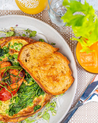 A breakfast setting of Green Egg Omelette with Pesto, Spinach, Peas and Grilled Chorizo