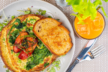 A breakfast setting of Green Egg Omelette with Pesto, Spinach, Peas and Grilled Chorizo