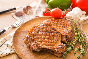 Plate with cooked pork steaks on table, closeup