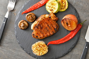 Cooked pork steak and vegetables on slate plate